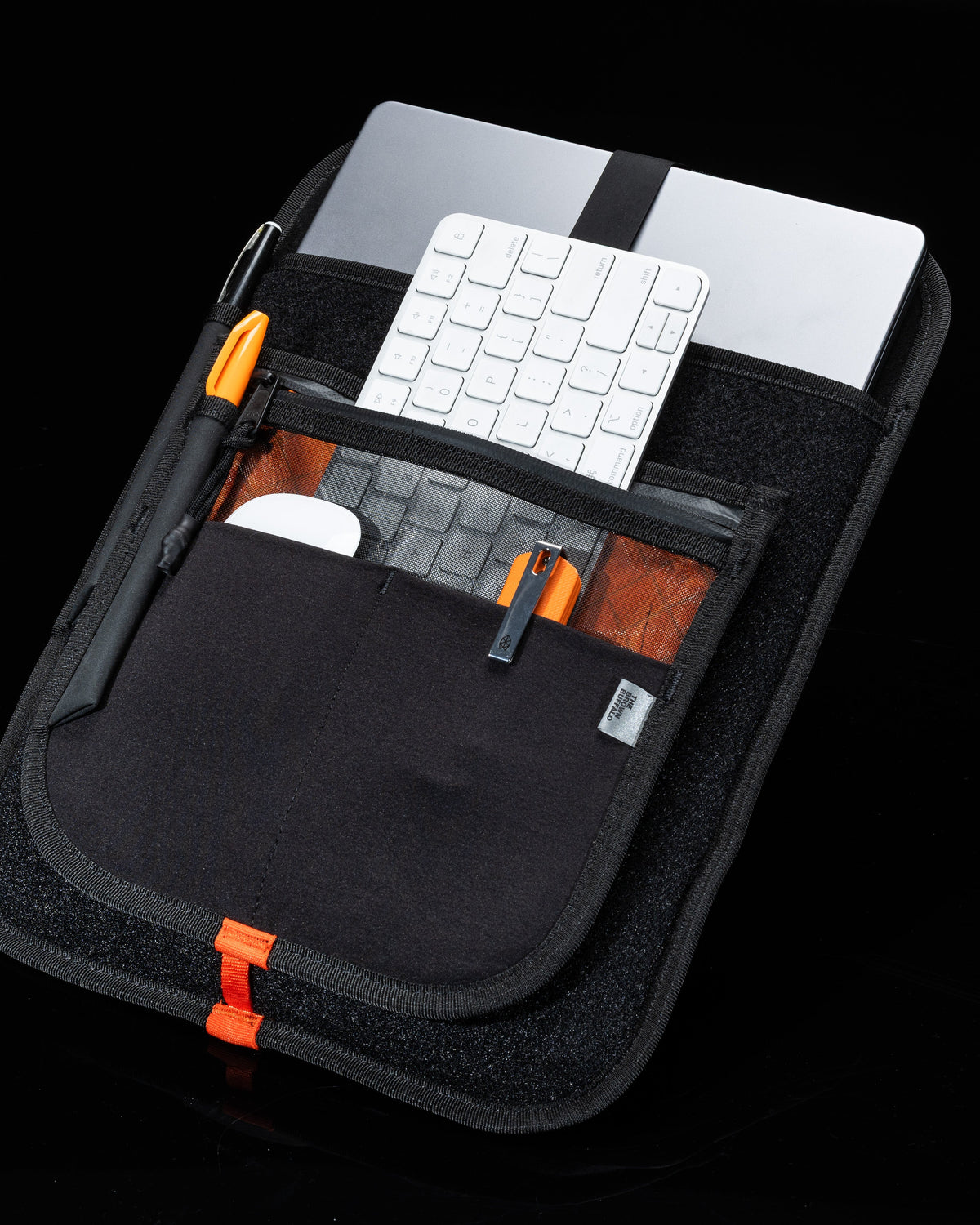 MOD 002 organizer backpack black with orange zippers; holds silver laptop and white keyboard on Tampa Home & Garden Store