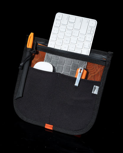 MOD 002 backpack black with orange zipper pulls, front pocket holds white wireless keyboard on Tampa Home & Garden Store