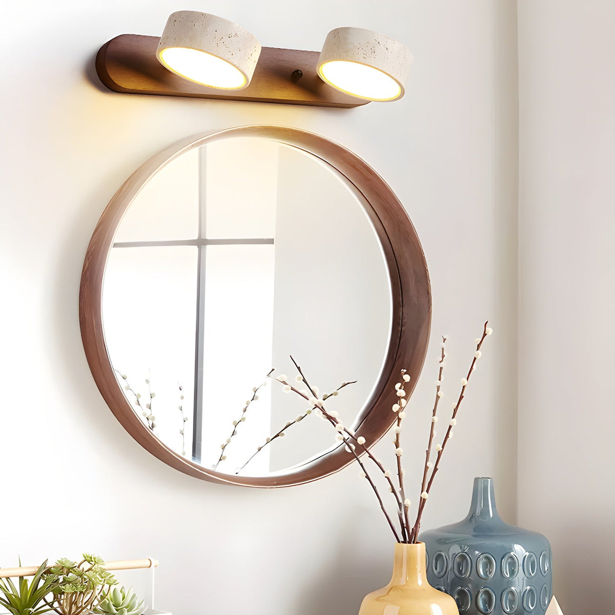 Moktan Sabai travertine stone wall light with dual lamps and wood accent above round mirror on Tampa Home & Garden Store