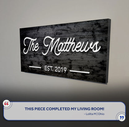 Family Name Sign V canvas with The Matthews in white cursive on rustic wood Tailored Canvases on Tampa Home & Garden Store