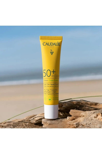 Caudalie Vinosun SPF 50+ sunscreen tube, bright yellow with white cap on a beach rock on Tampa Home & Garden Store