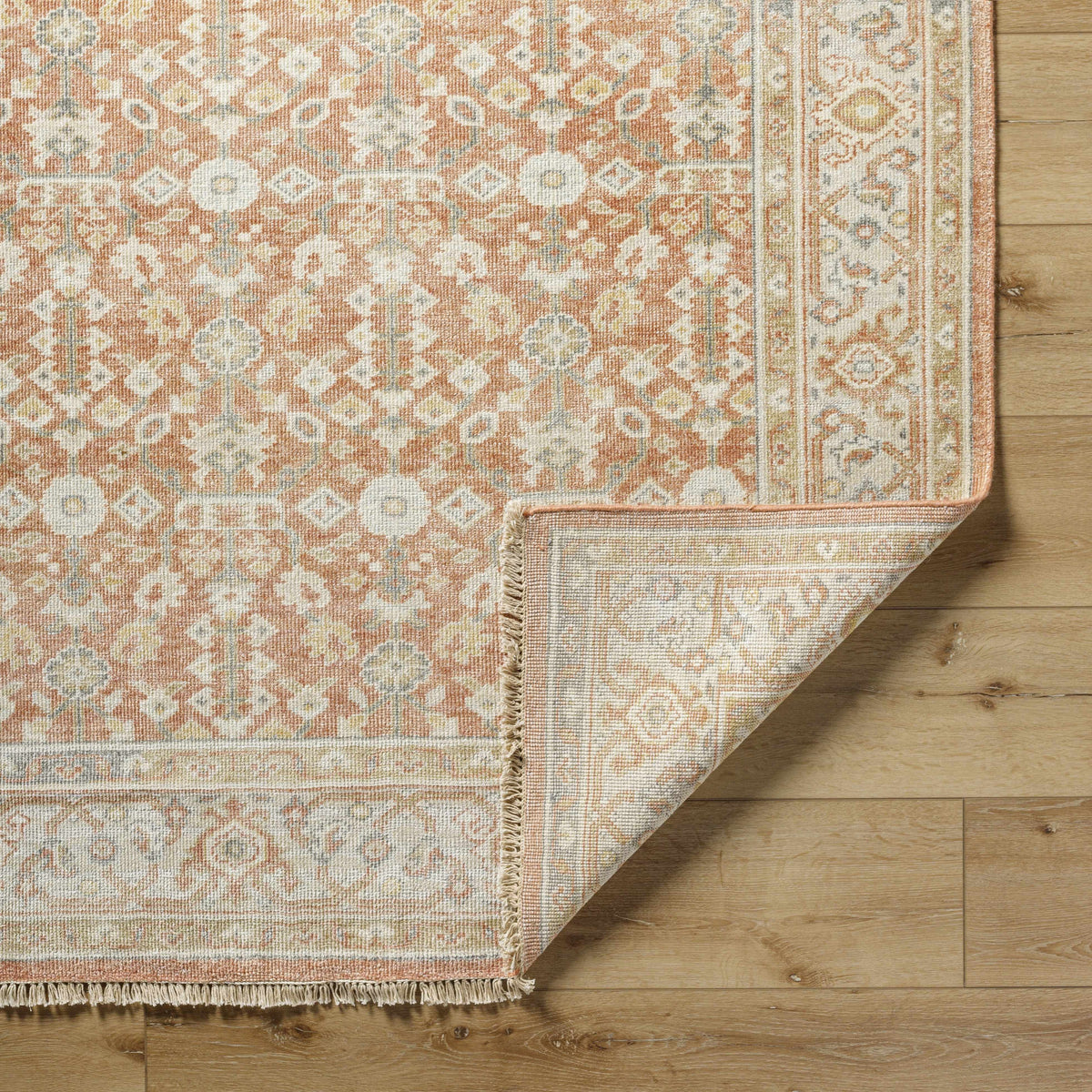 Wailea Area Rug by Boutique Rugs orange ivory oriental pattern with fringe on wood floor on Tampa Home & Garden Store