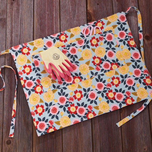 Gardener's Half Apron floral print by Womanswork on light blue fabric with pink gloves on Tampa Home & Garden Store