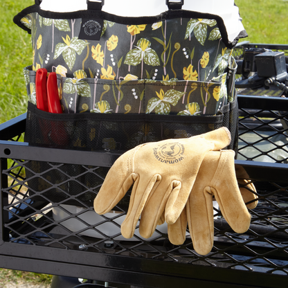 Tan leather work gloves draped over floral gardening tote with red-handled tools and Womanswork on Tampa Home & Garden Store