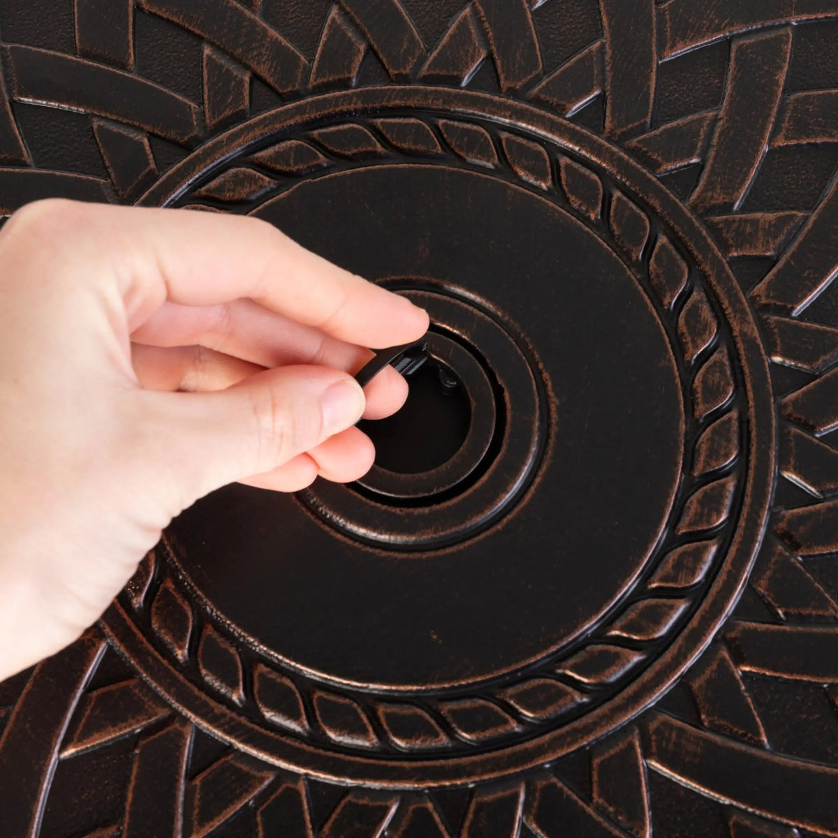 Wagner 33-inch round aluminum LPG fire pit gas valve being turned on bronze-textured surface on Tampa Home & Garden Store