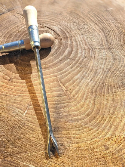 Weeding fork with wooden handle and steel two-prong tines on a textured wooden log background on Tampa Home & Garden Store