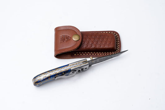 Hand-engraved folding knife with Damascus-inspired blade and brown leather sheath by Titan K on Tampa Home & Garden Store