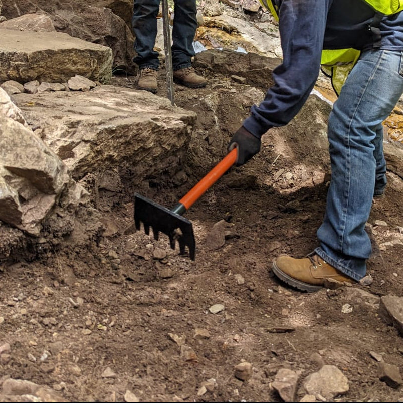 Clyde Jr rake by Backslope Tools with orange handle and black tined head used on rocky soil on Tampa Home & Garden Store