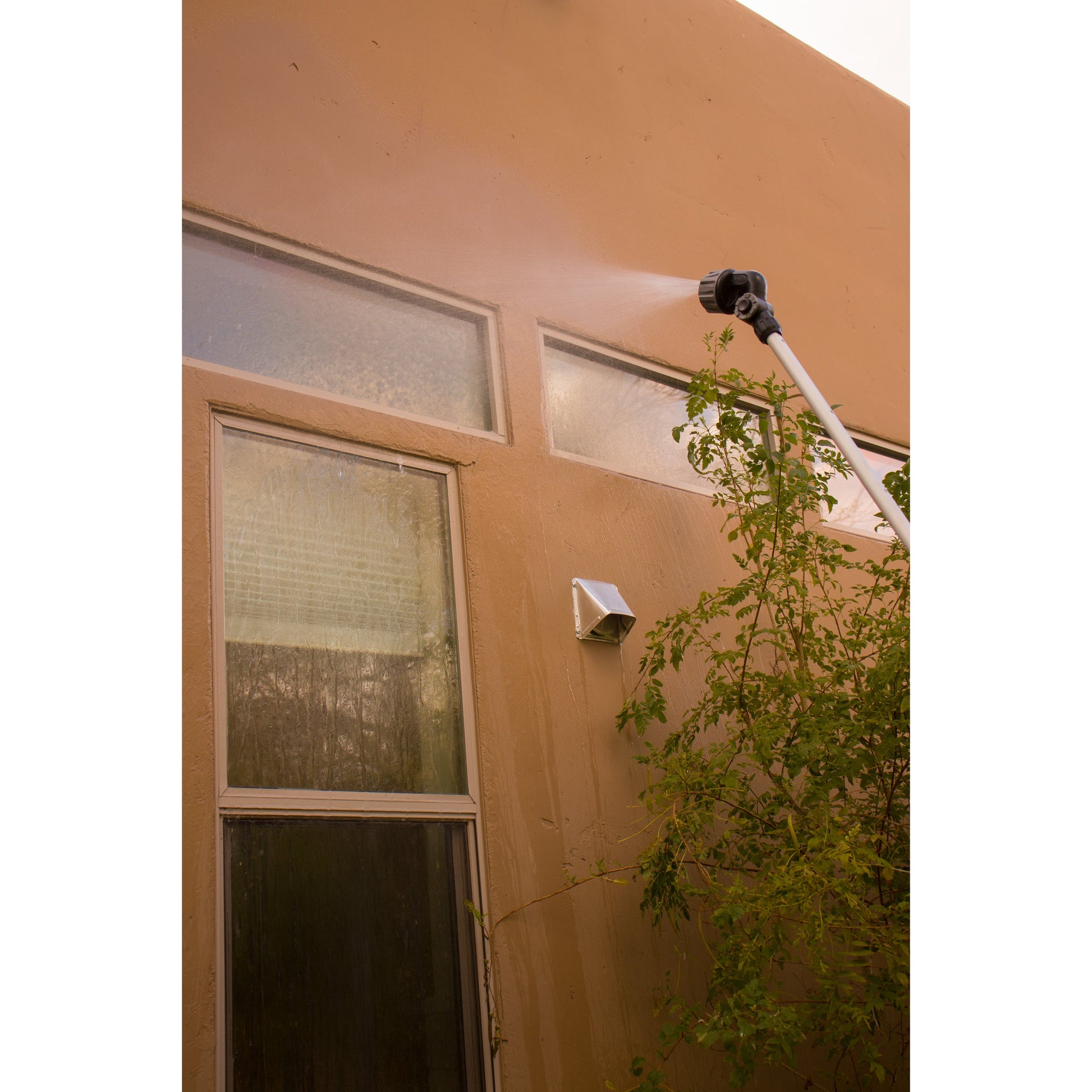 X-Stream 72in Telescoping 4-Pattern Watering Wand Orbit Irrigation spraying orange stucco wall on Tampa Home & Garden Store