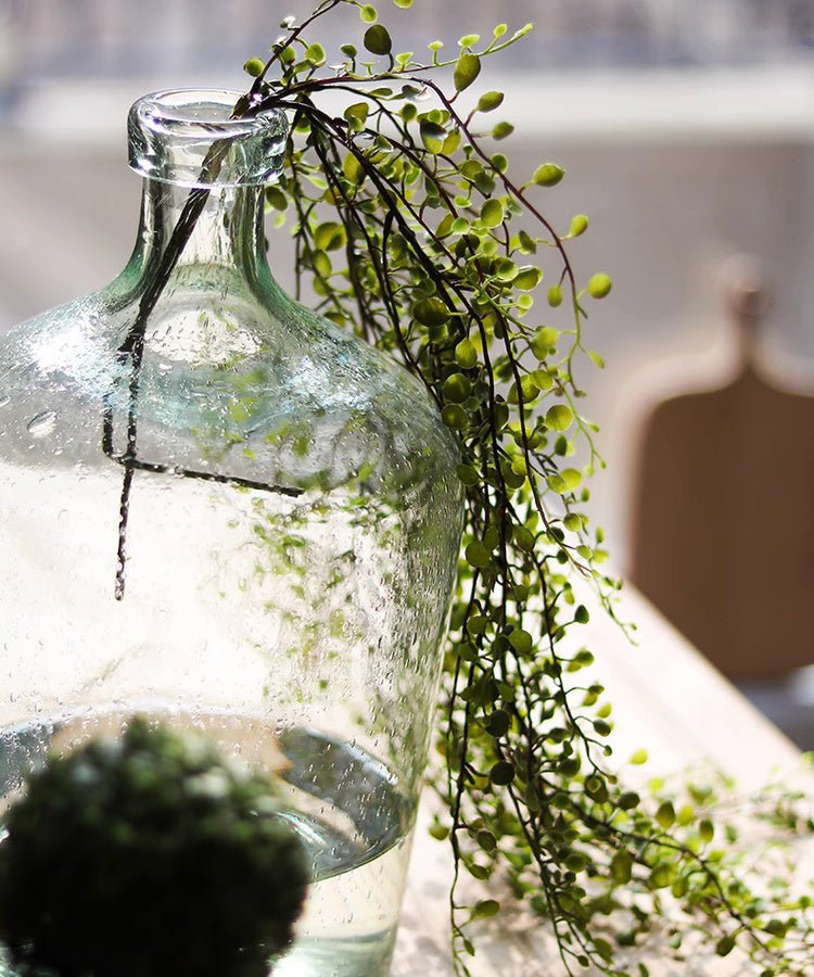 Hanging faux mini leaf garland, 27.5in, green leaves draped over a glass bottle on Tampa Home & Garden Store