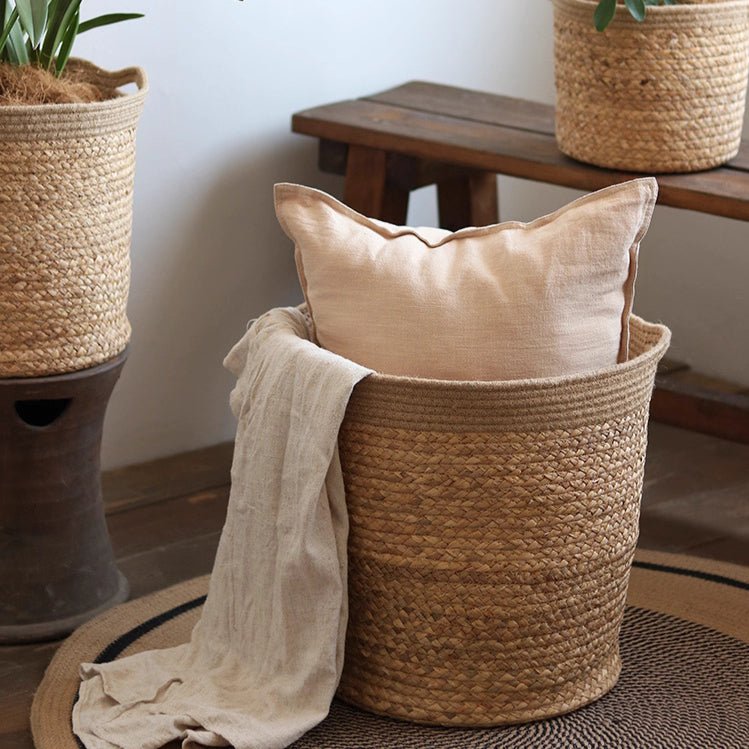 Natural cylinder storage and planter basket made of woven jute with beige cushion and throw on Tampa Home & Garden Store