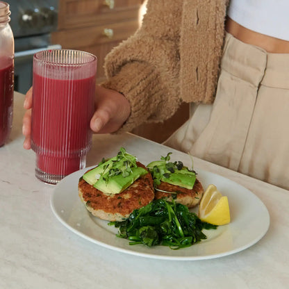 4-Day Shake Reset cleanse plate with avocado-topped veggie patties, greens, lemon, and red juice in a ribbed glass on Tampa Home & Garden Store