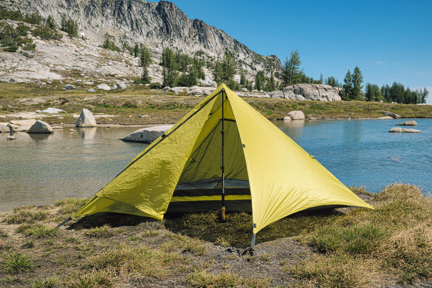 Trekker Pyramid 1-person backpacking tent, bright yellow pitched near a lake with rocky mountains on Tampa Home & Garden Store
