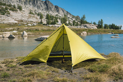Trekker Pyramid 1-person backpacking tent, bright yellow pitched near a lake with rocky mountains on Tampa Home & Garden Store