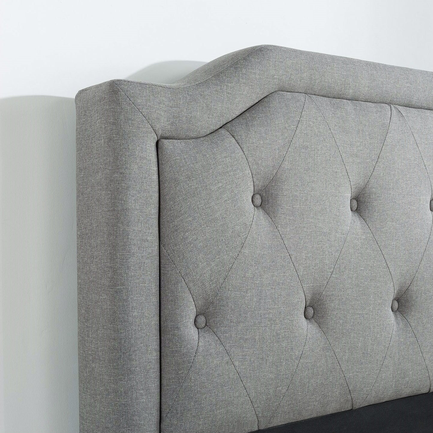 Cama king size con plataforma tapizada en gris y cabecero clásico con botones capitoné