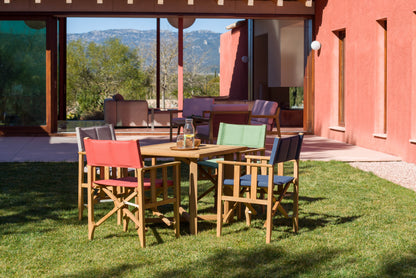 Zircon teak director chairs with colorful fabric seats around a round wooden table on a lawn on Tampa Home & Garden Store