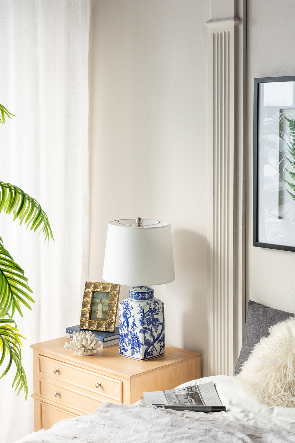 Blue and white ceramic vase lamp with pattern and white shade on a light wood dresser on Tampa Home & Garden Store