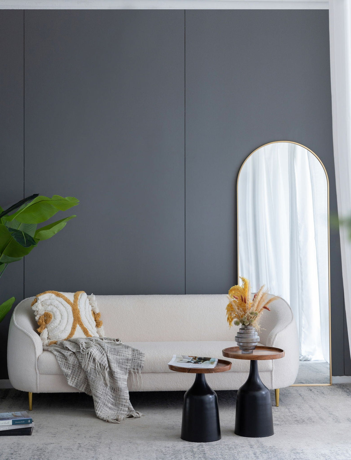 The Celine arch body mirror with slim gold frame leaning on a gray wall in a modern living room on Tampa Home & Garden Store