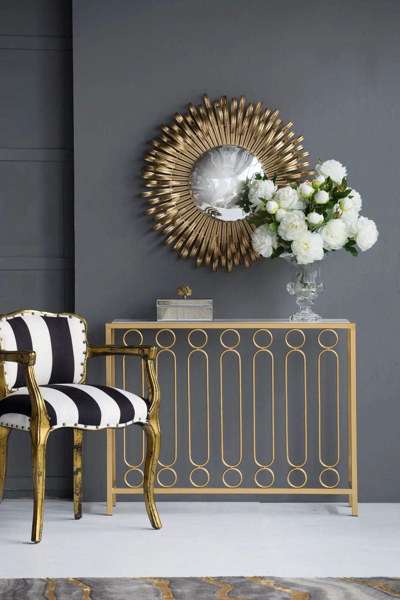 Sunburst Gold Wall Mirror by Unique Piece Furniture on dark wall with white bouquet vase on Tampa Home & Garden Store