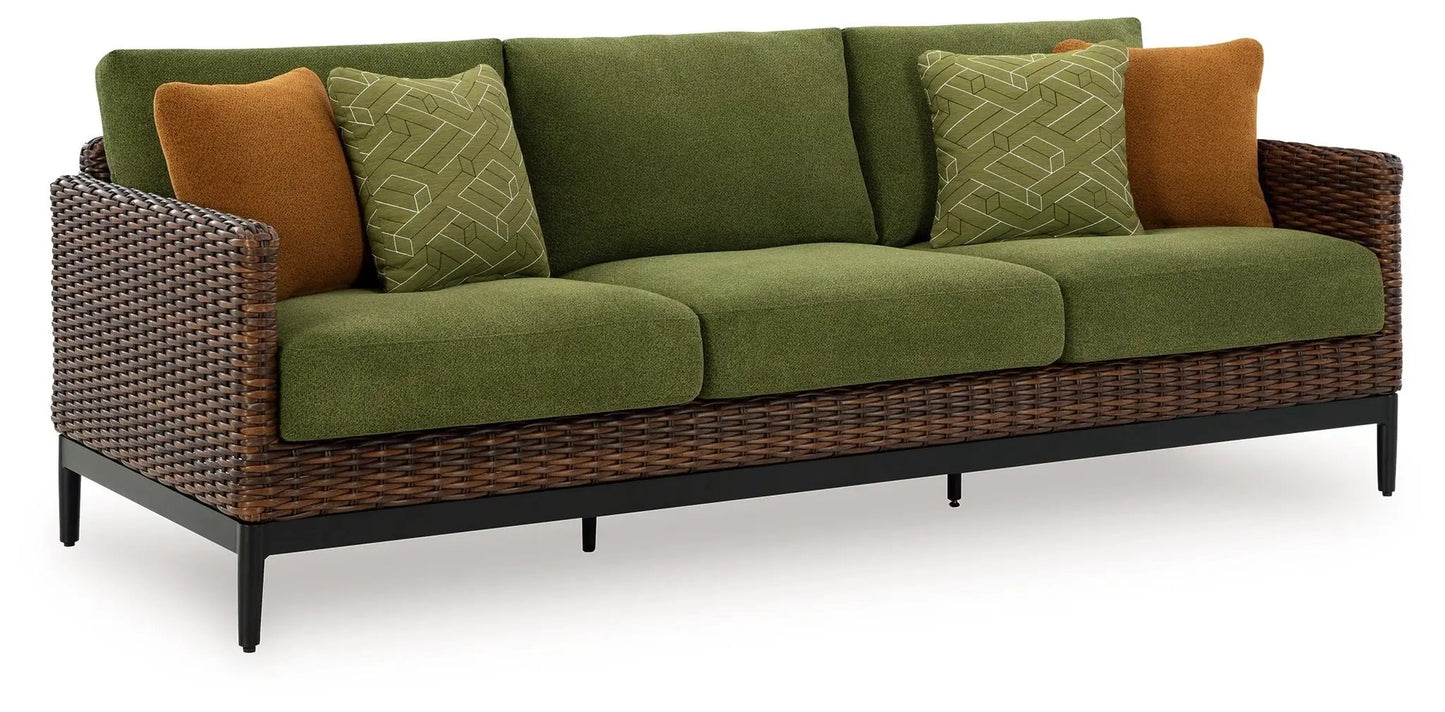 Horizon Hall sofa with green cushions and brown pillows in a woven wicker frame on Tampa Home & Garden Store