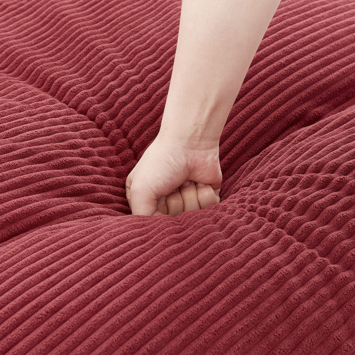 Swivel barrel chair burgundy corduroy upholstery with plush texture and a hand for scale on Tampa Home & Garden Store