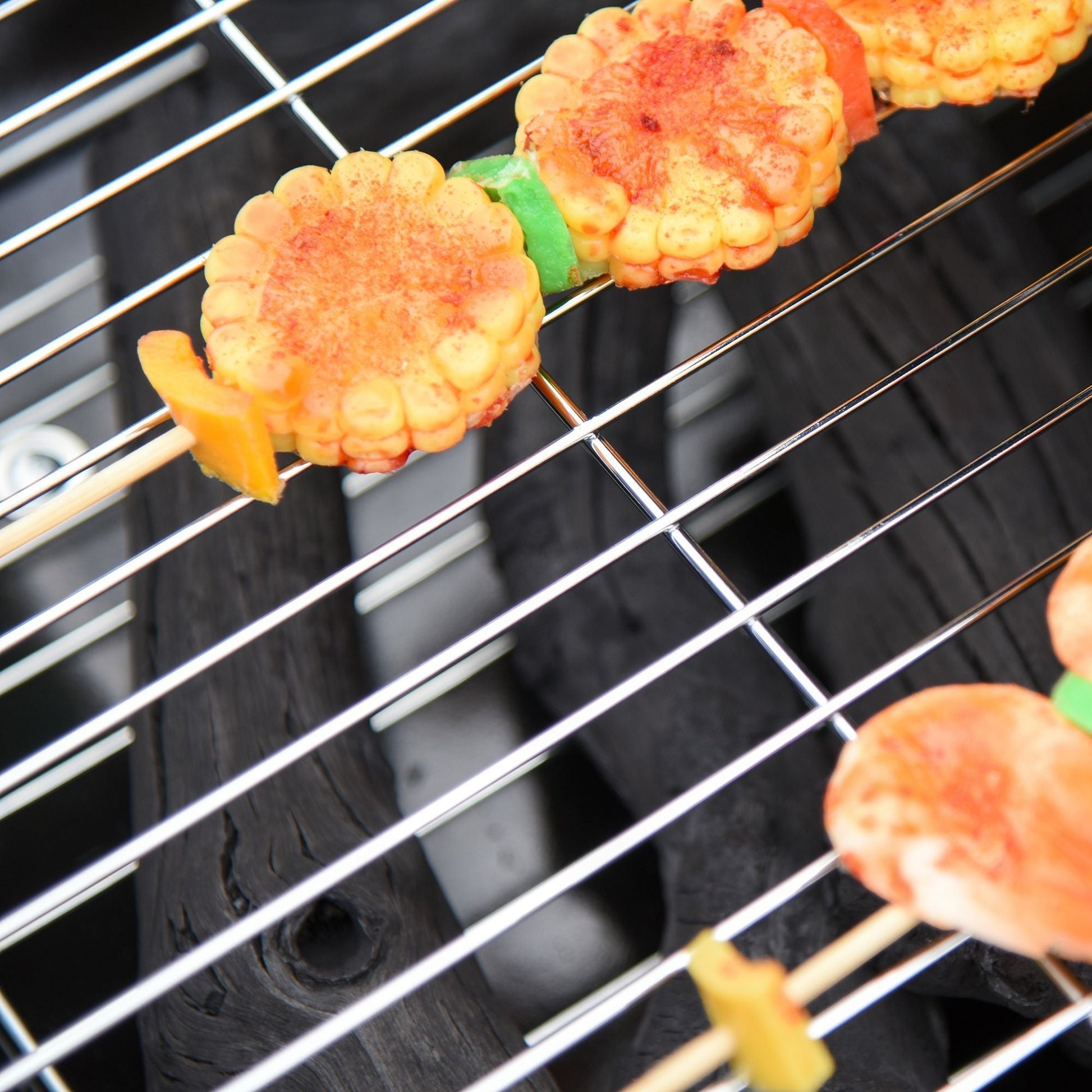 Outsunny 21' portable charcoal grill corn kebabs on a metal grill rack seasoned with red spice on Tampa Home & Garden Store