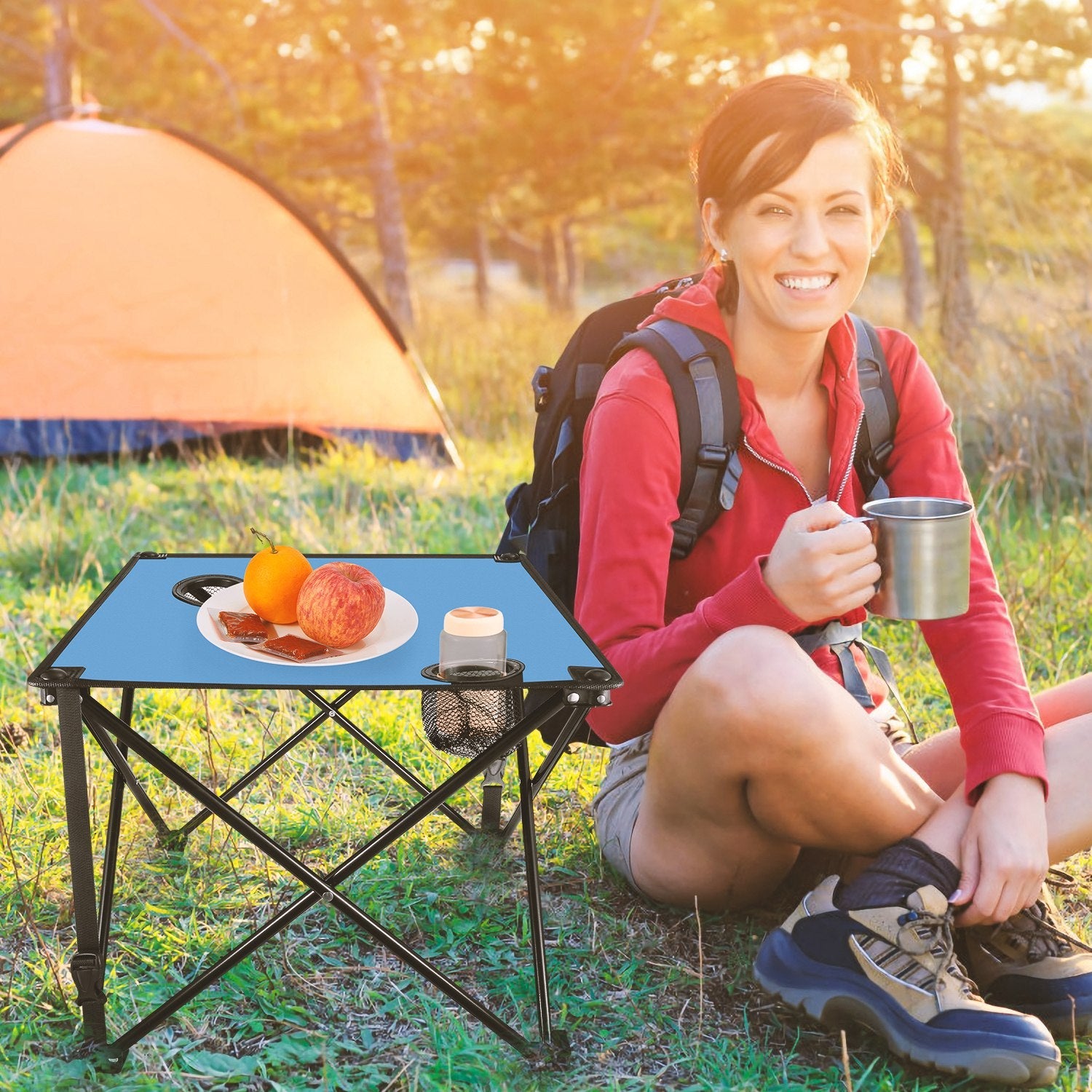 GemGear foldable camping table with blue top, two cup holders and carrying bag beside a hiker on Tampa Home & Garden Store