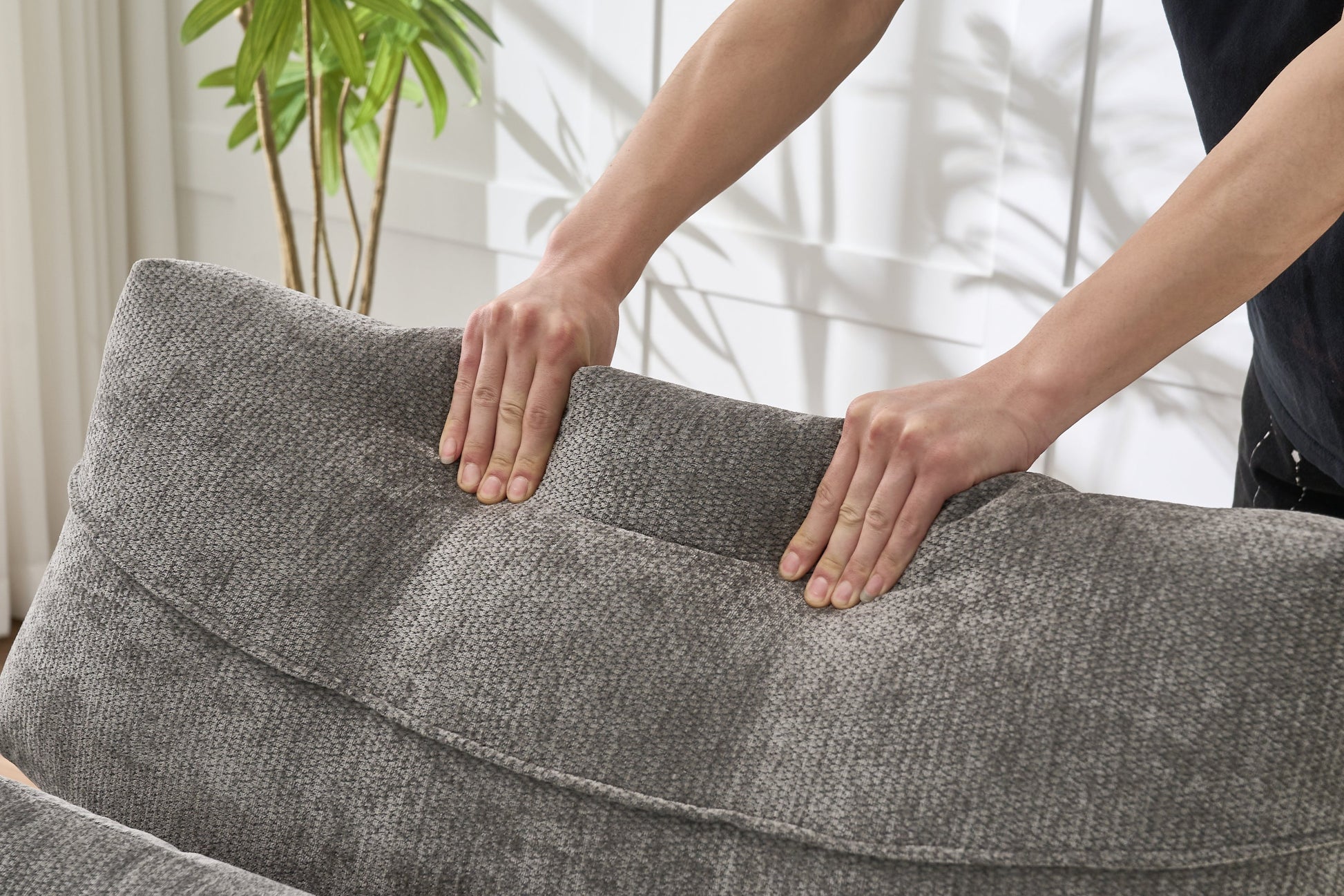Modern grey upholstered chaise lounge sofa recliner in textured fabric with hands pressing edge on Tampa Home & Garden Store