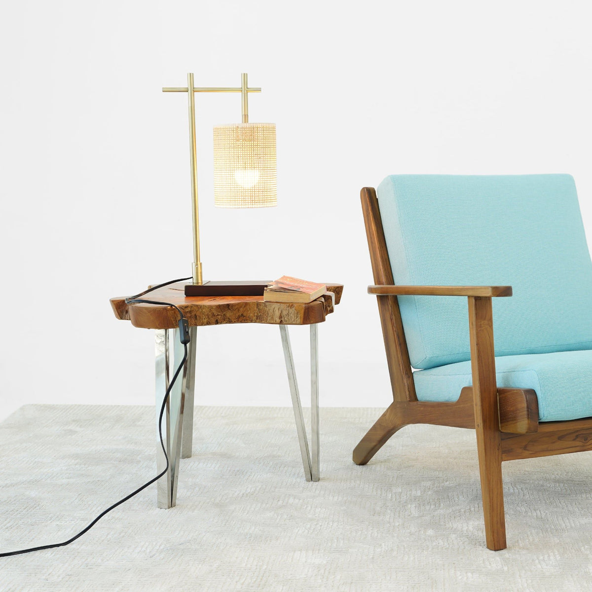 Bronze bedroom table lamp with woven shade on a wooden side table beside a turquoise chair on Tampa Home & Garden Store