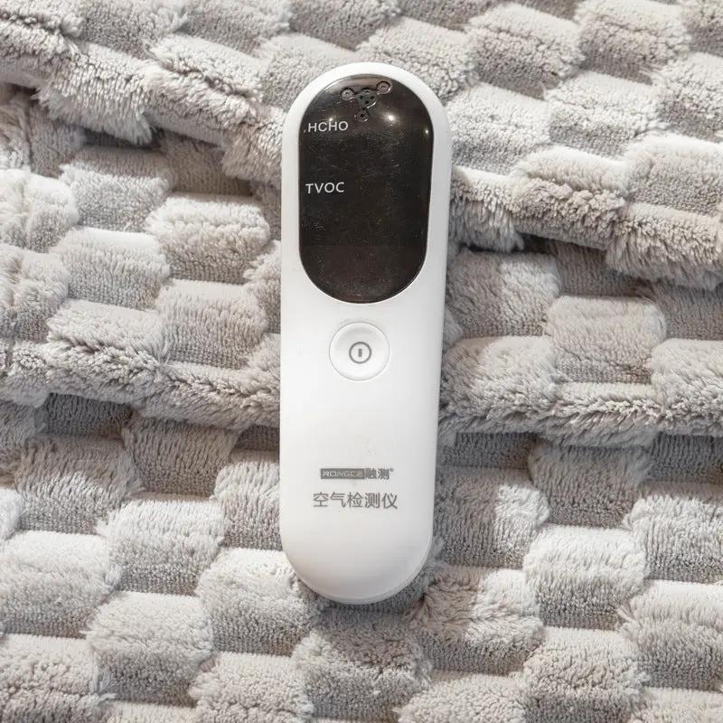 White handheld air quality detector with black display shows HCHO and TVOC on beige sofa cushion on Tampa Home & Garden Store