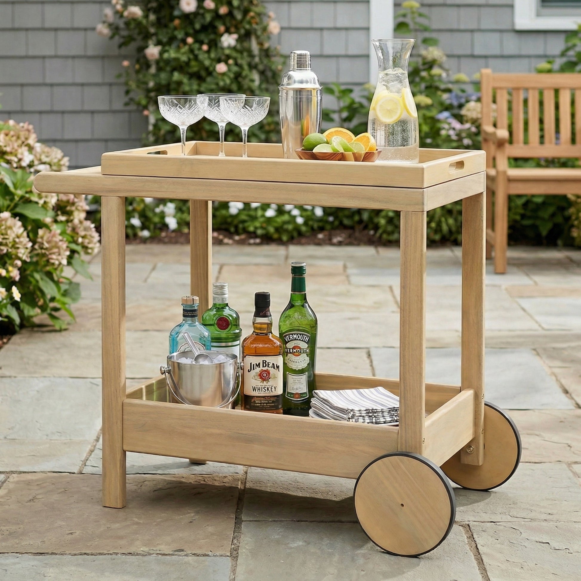 Saratoga Outdoor Rolling Bar Cart in natural wood finish with wheels, liquor bottles and glassware on Tampa Home & Garden Store