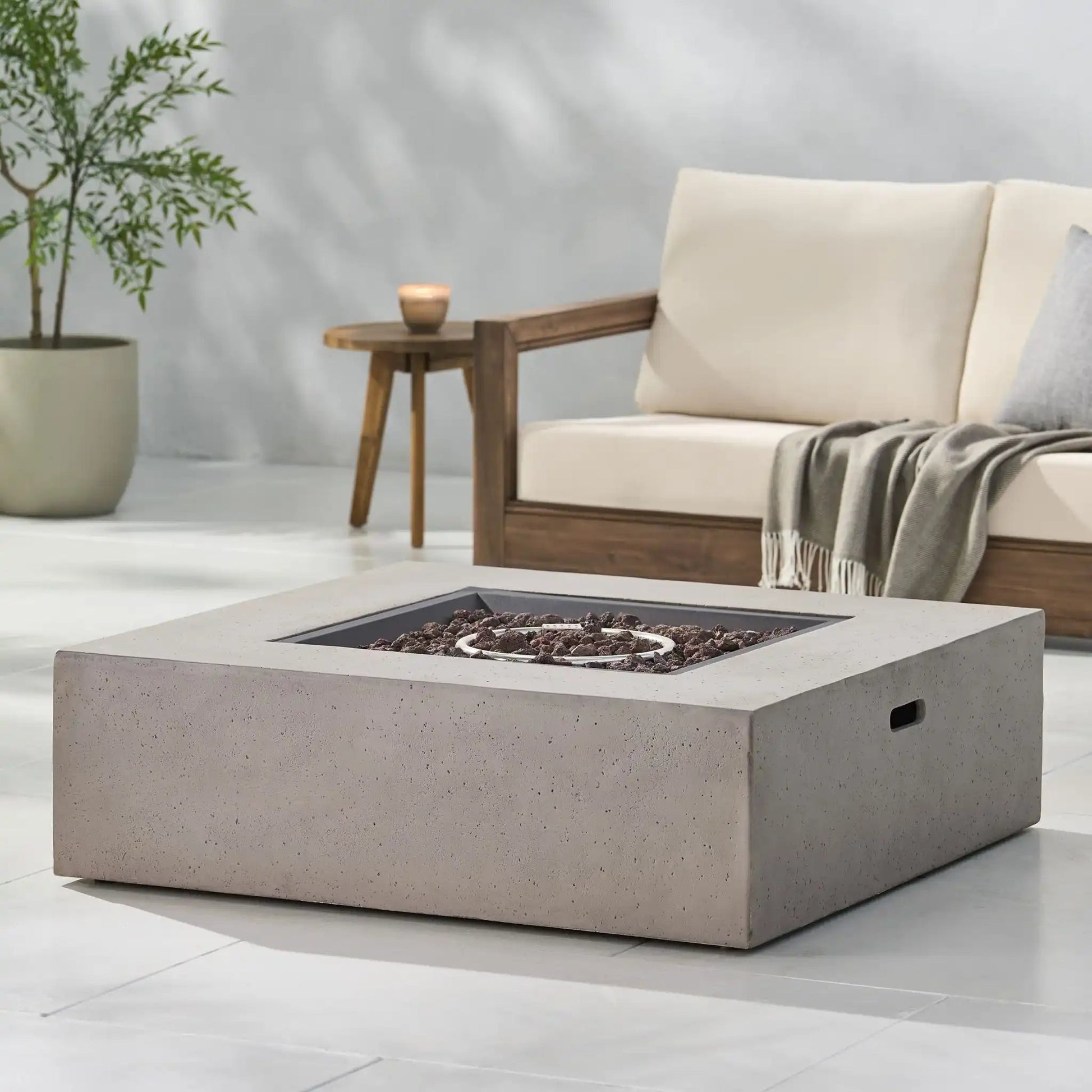 Modern 50,000 BTU square concrete propane fire table with lava rock bed in a cozy living room on Tampa Home & Garden Store