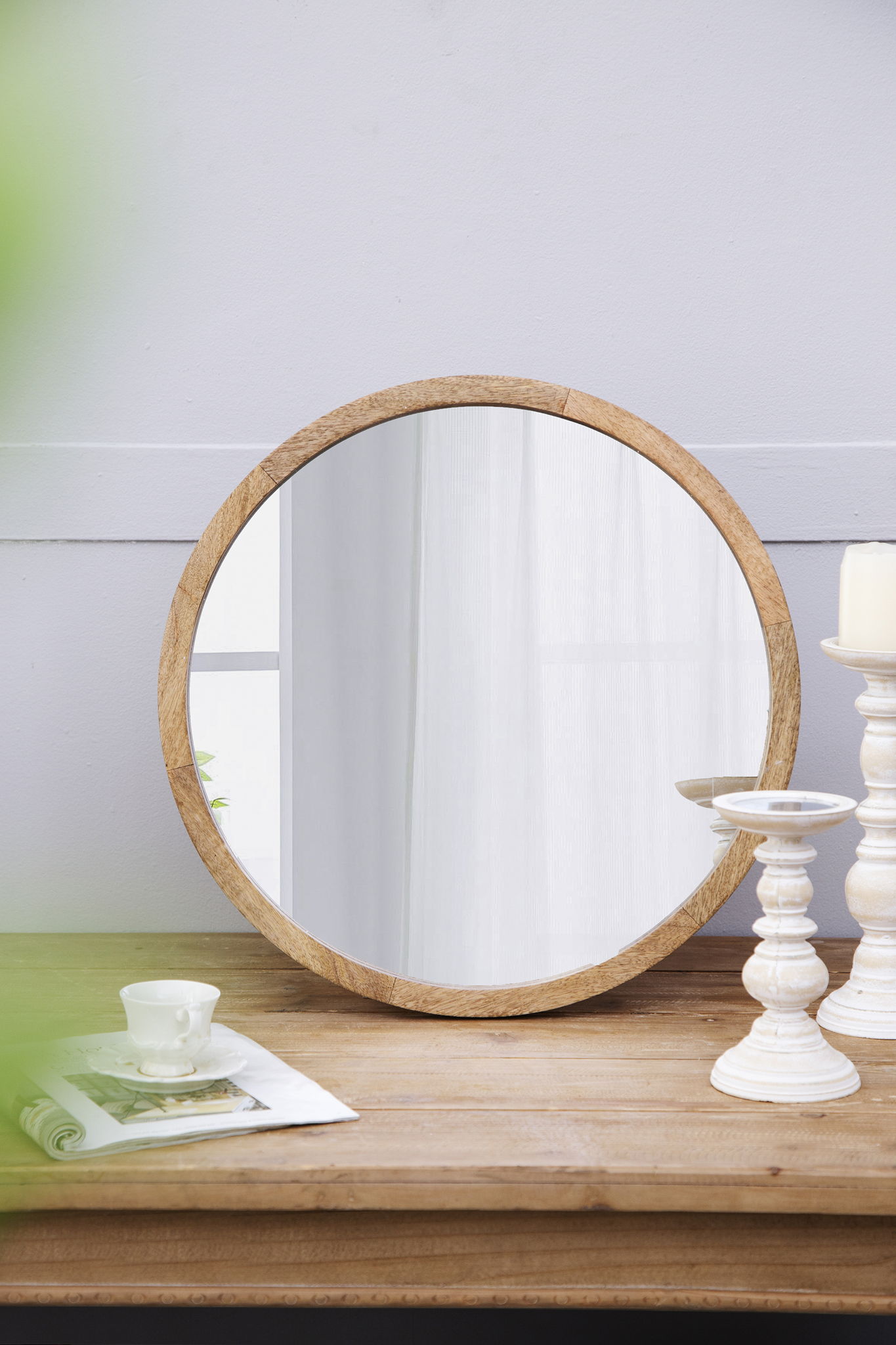 Circular wall mirror with natural wooden frame on a wooden table in a cozy living room on Tampa Home & Garden Store