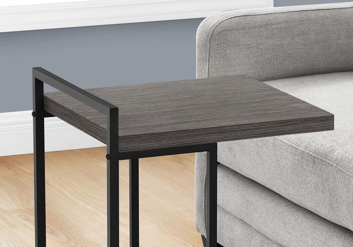 Accent table, C-shaped with dark wood grain top and black metal frame beside a gray sofa on Tampa Home & Garden Store