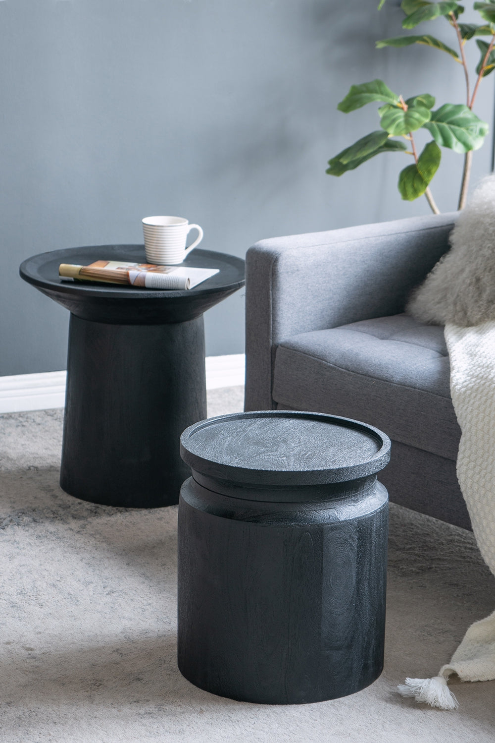Black wooden cylinder nightstands with round tops beside a gray sofa HouseOfZazla on Tampa Home & Garden Store