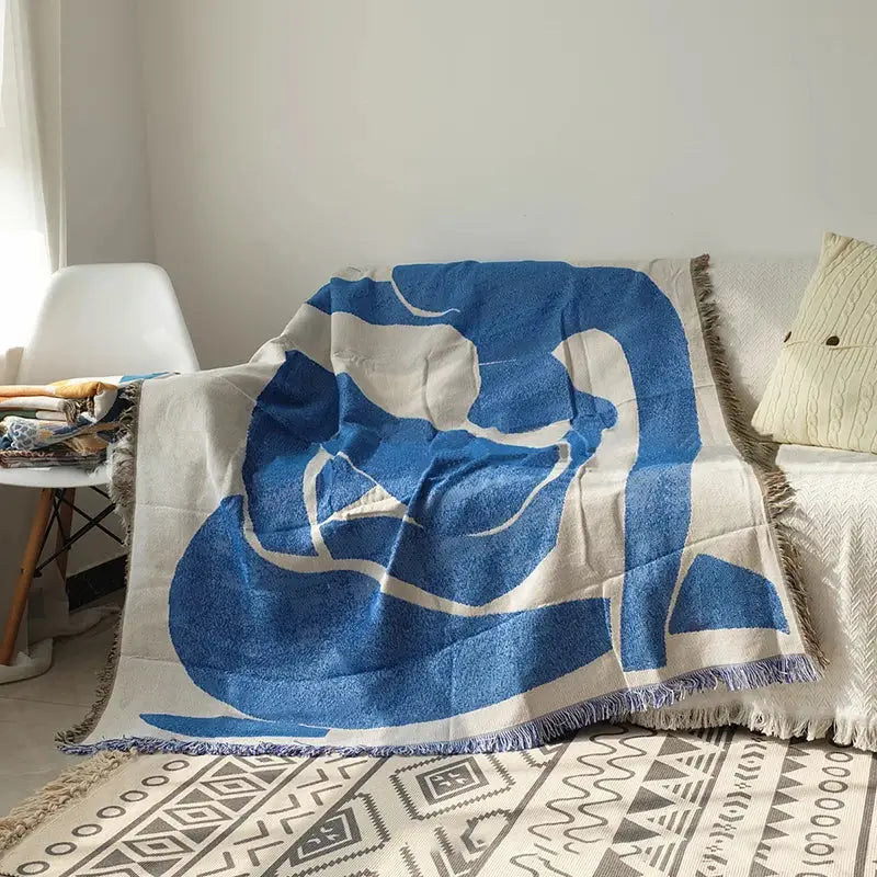 Blue geometric knitted throw blanket by Decorbites with fringe edges draped over a white sofa on Tampa Home & Garden Store