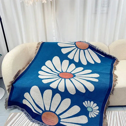 Blue geometric knitted throw with white daisy pattern and fringe on beige sofa on Tampa Home & Garden Store