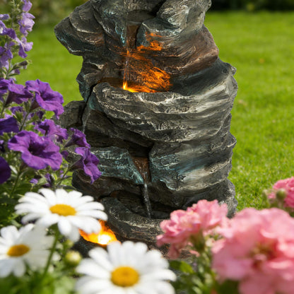 6-tier outdoor cascading stone water fountain with 3 LED lights amid purple flowers on Tampa Home & Garden Store