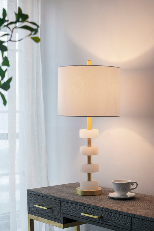Marble table lamp with stacked marble discs, brass stem and beige shade on a dark console on Tampa Home & Garden Store