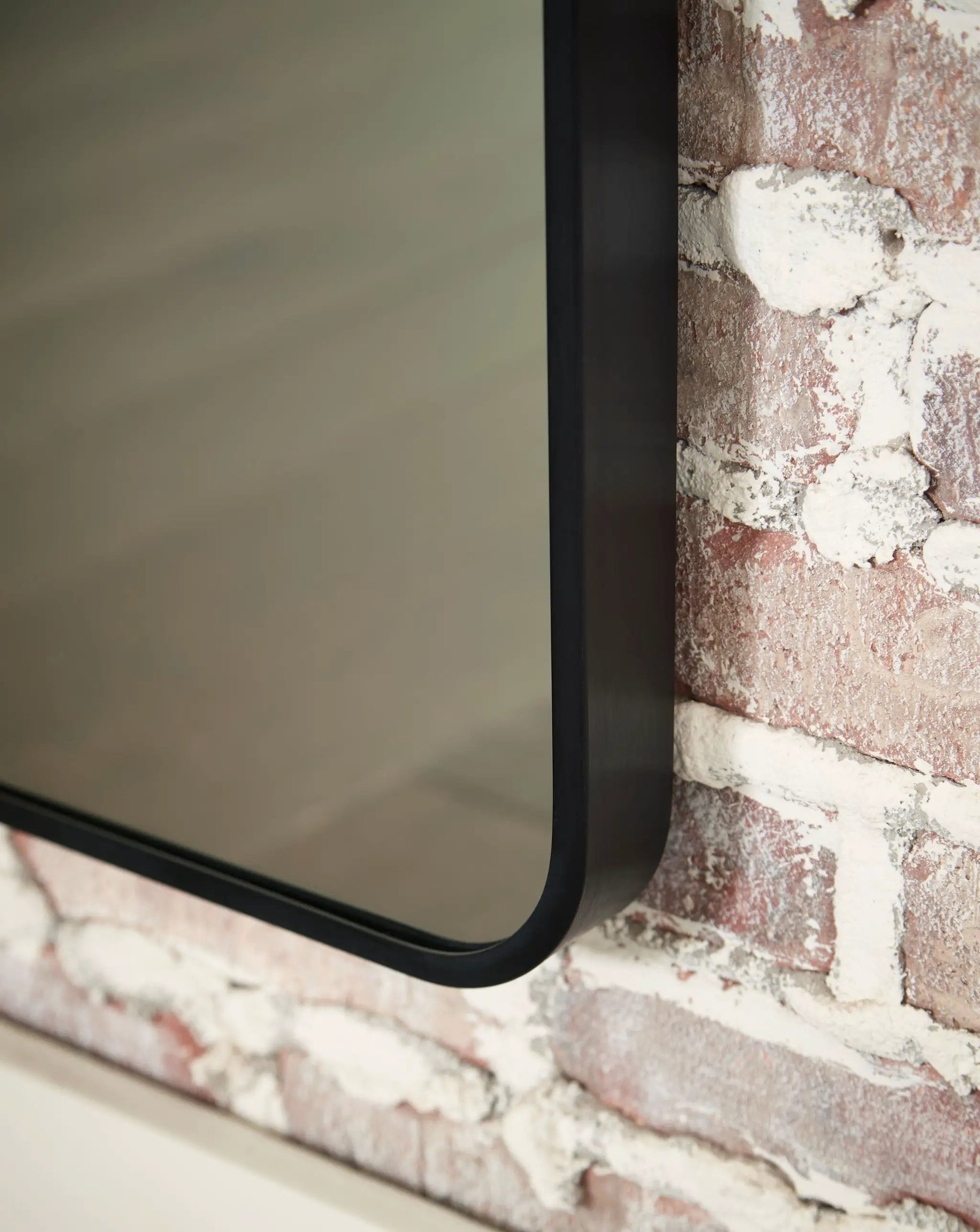 Sethall Floor Mirror from Unique Piece Furniture in black curved-frame with brick backdrop on Tampa Home & Garden Store