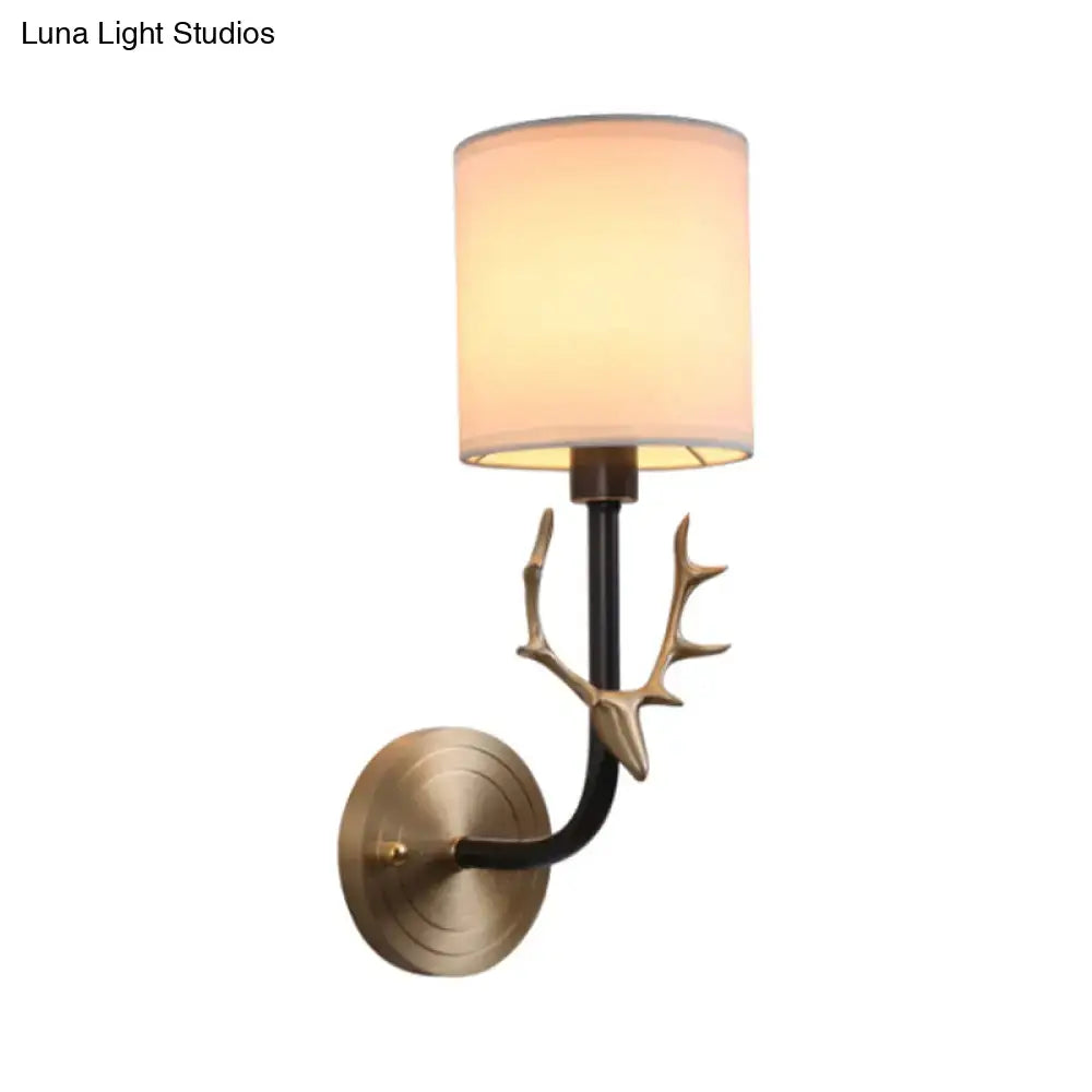 Antique Brass Sconce with beige shade, black curved arm and brass antler accent on wall mount on Tampa Home & Garden Store