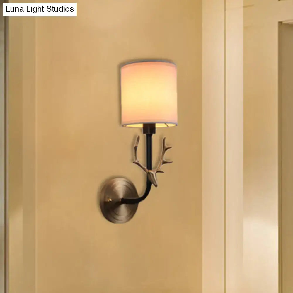 Antique brass fabric sconce with curved black arm and leaf accents on Tampa Home & Garden Store