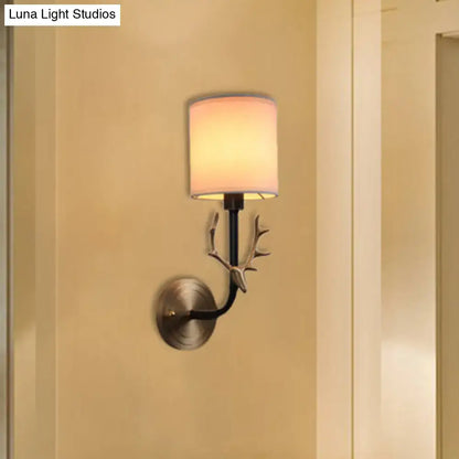 Antique brass fabric sconce with curved black arm and leaf accents on Tampa Home & Garden Store
