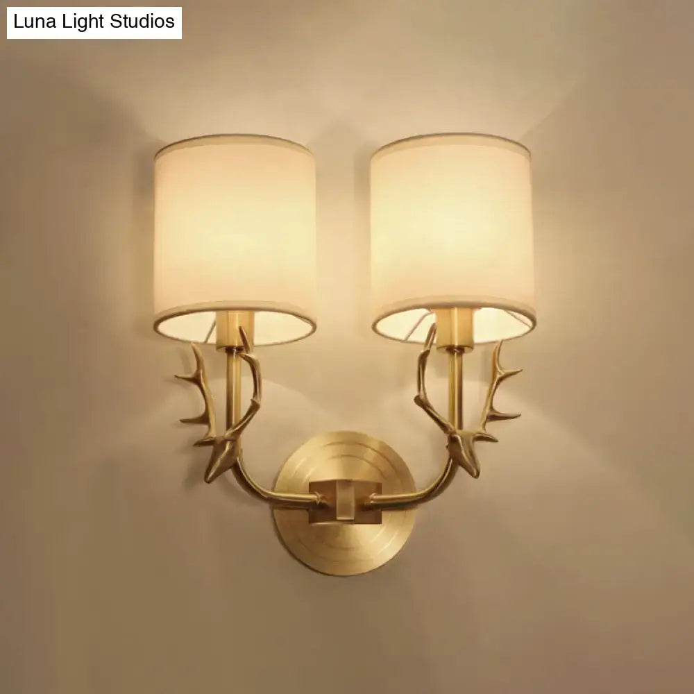 Antique brass fabric sconce with twin antler-style arms and white fabric shades; wall mount on Tampa Home & Garden Store