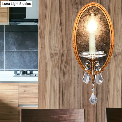 Antique brass candle-style wall sconce with oval mirrored backplate and crystal drops on Tampa Home & Garden Store