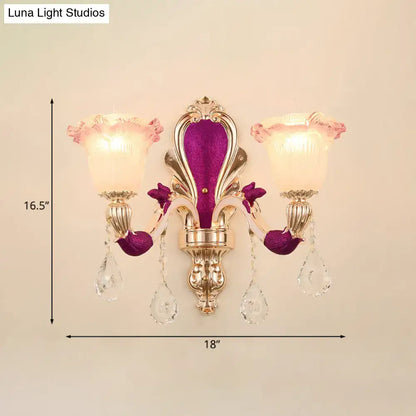 Gold double-arm wall sconce with purple velvet backplate, crystal drops and pink frosted glass shades on Tampa Home & Garden Store