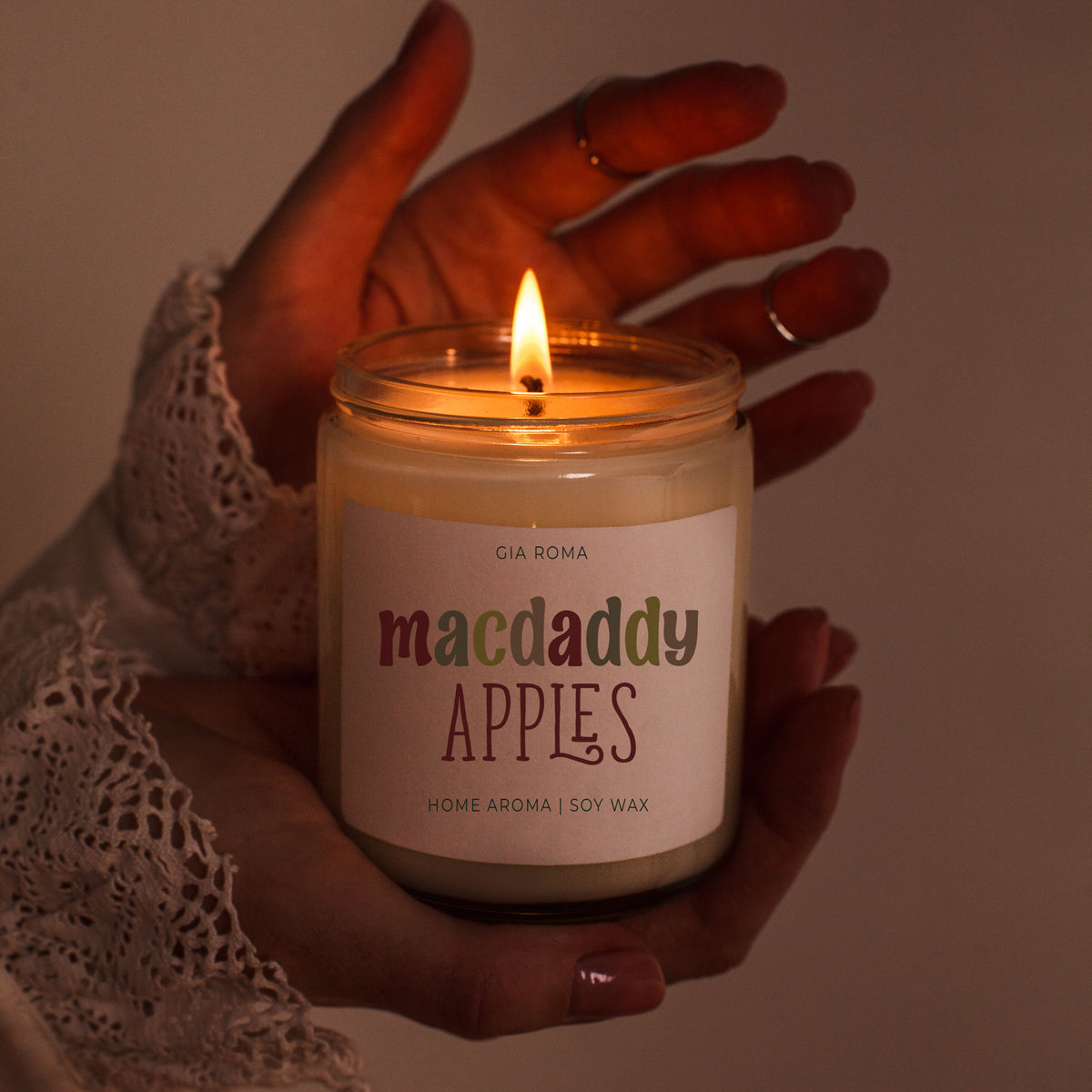 Candle Mac Apple by Gia Roma, macdaddy apples scent soy wax in a white jar with a lit wick held by lace-sleeve hands on Tampa Home & Garden Store