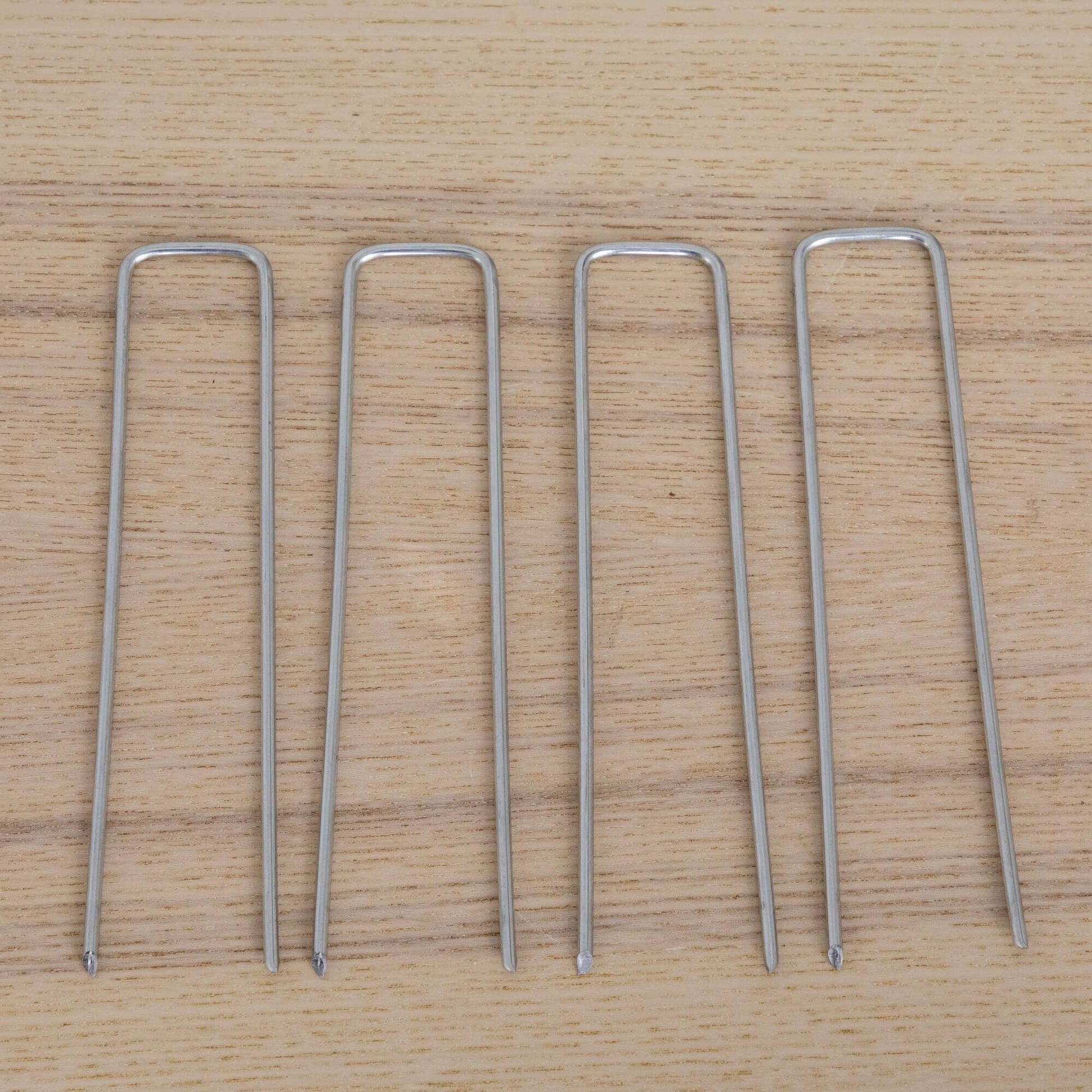 Silver U-shaped metal garden stakes arranged on a wooden surface on Tampa Home & Garden Store