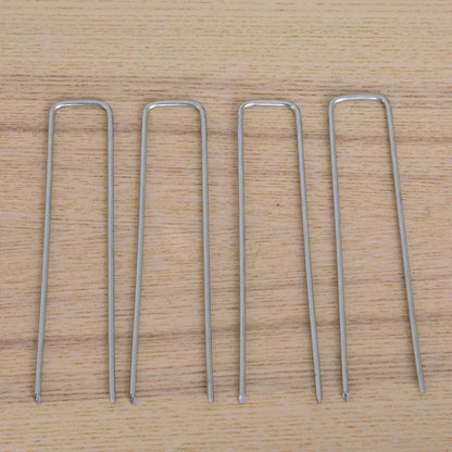 Silver U-shaped metal garden stakes arranged on a wooden surface on Tampa Home & Garden Store