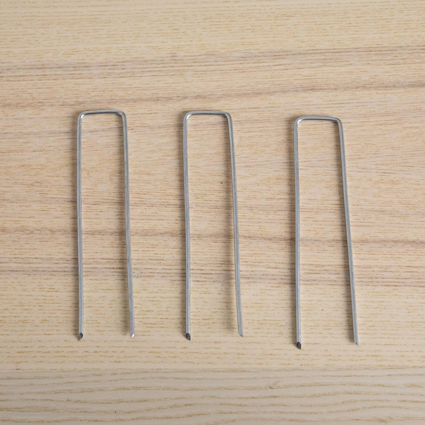 4-pack silver metal U-shaped plant stakes on light wood surface on Tampa Home & Garden Store